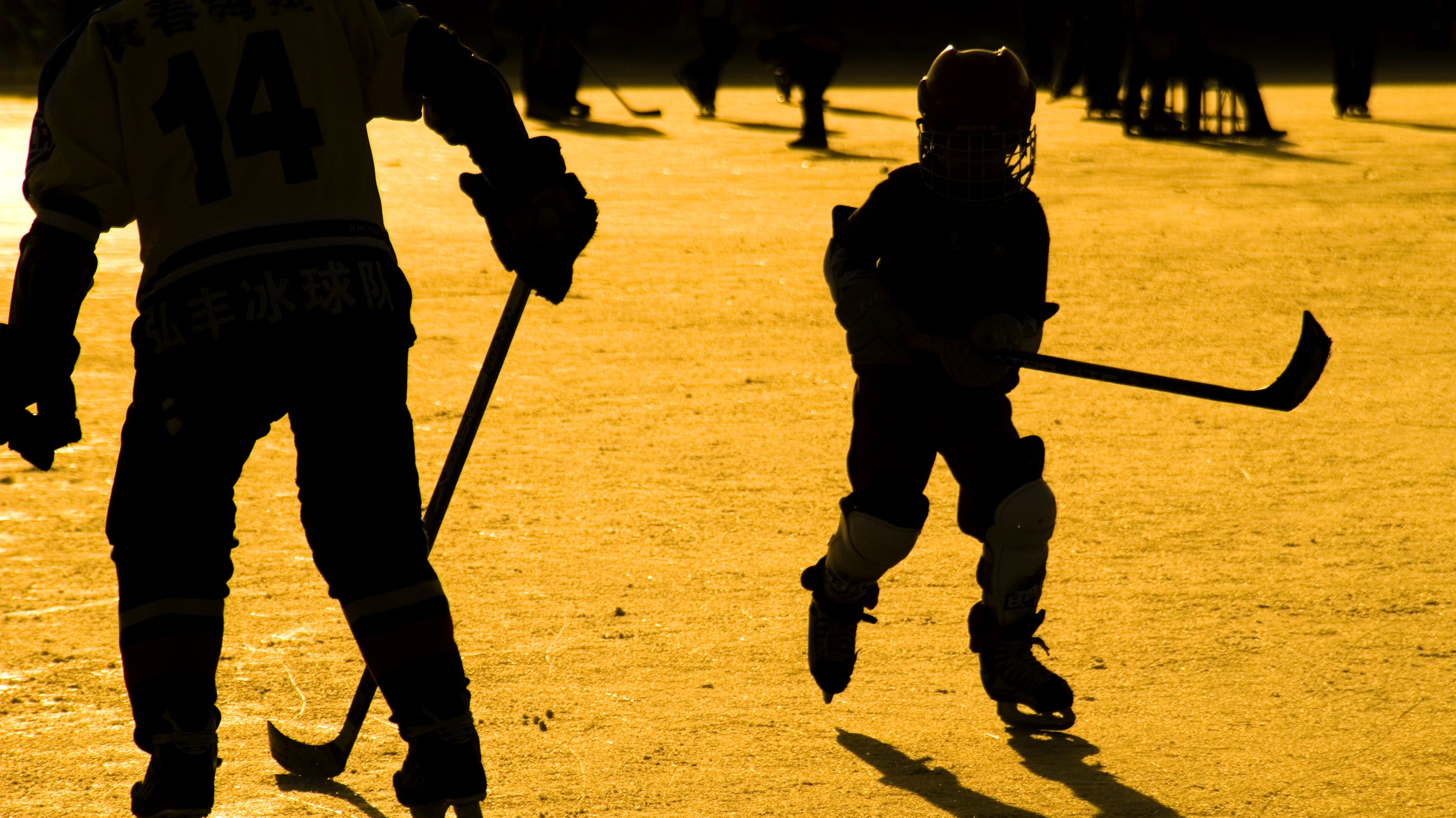 A kid playing hockey at sunset