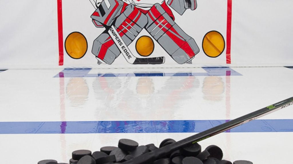 Pile of hockey pucks ready to be used with Snipers Edge dryland hockey tiles and shooting tarp