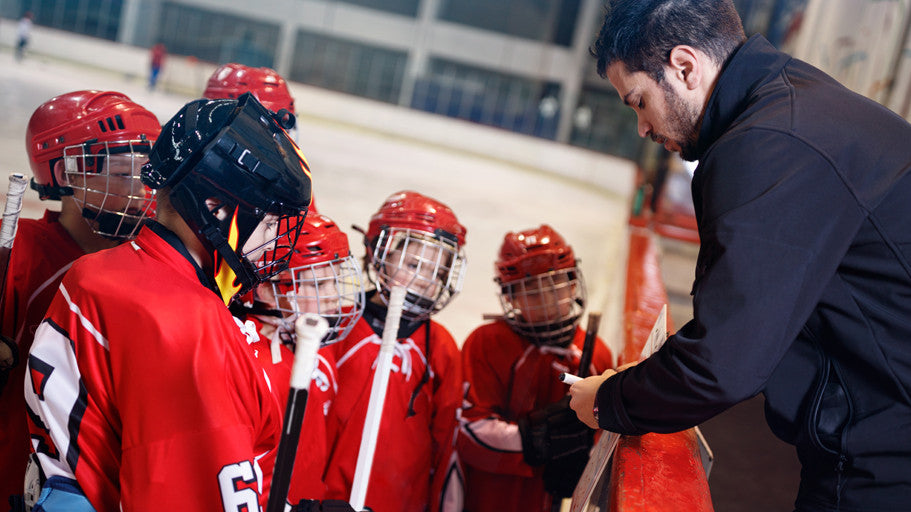 A coach speaking to a group of kids hockey players