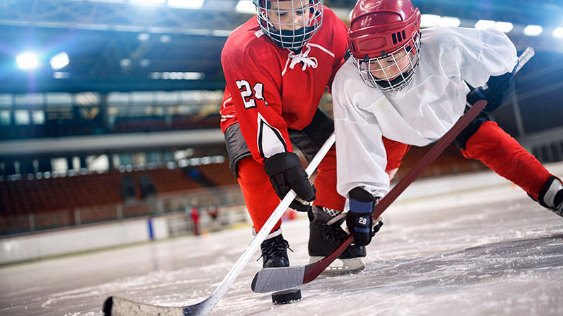 Two kids playing hockey using their sticks in the game
