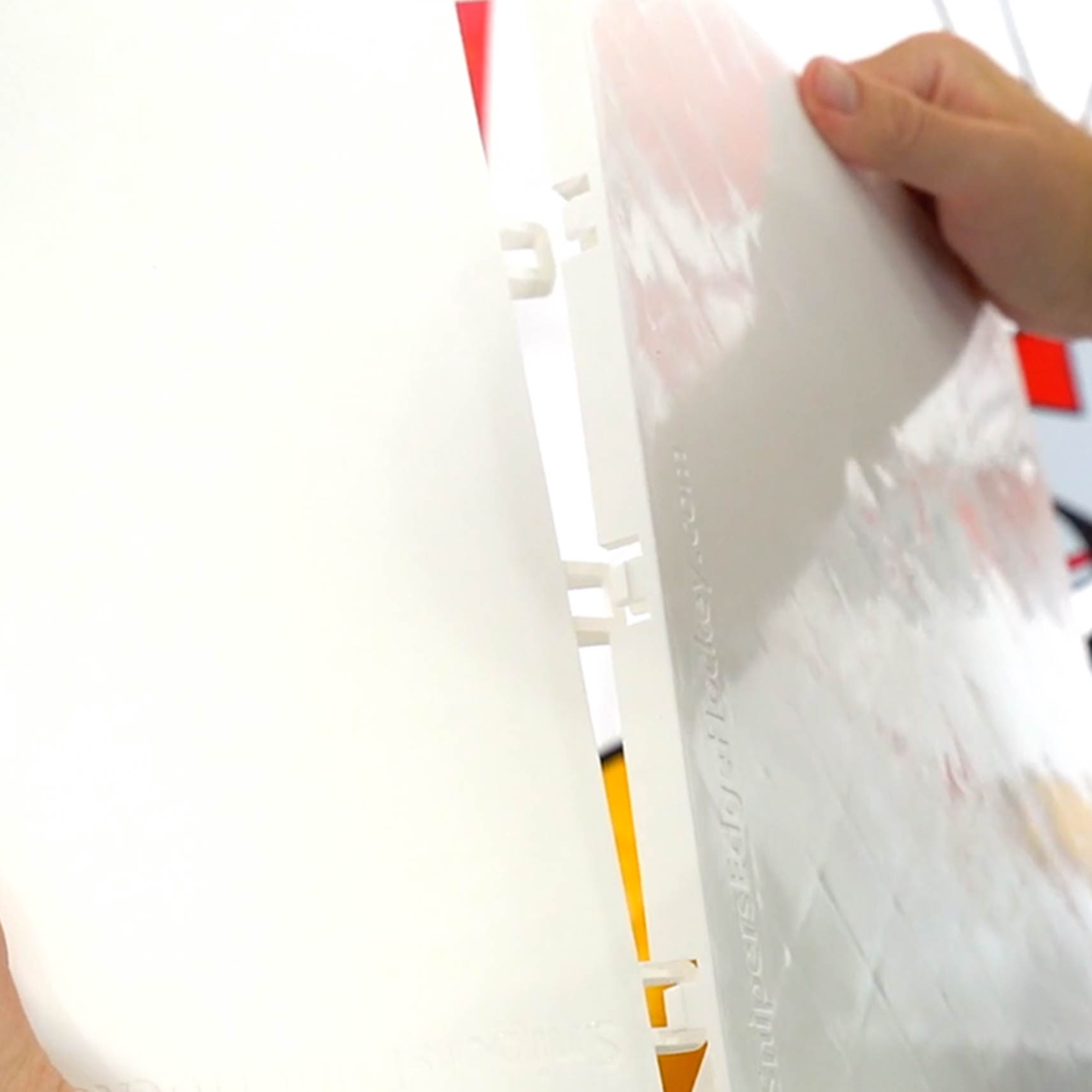 a person snapping together two white slick tiles