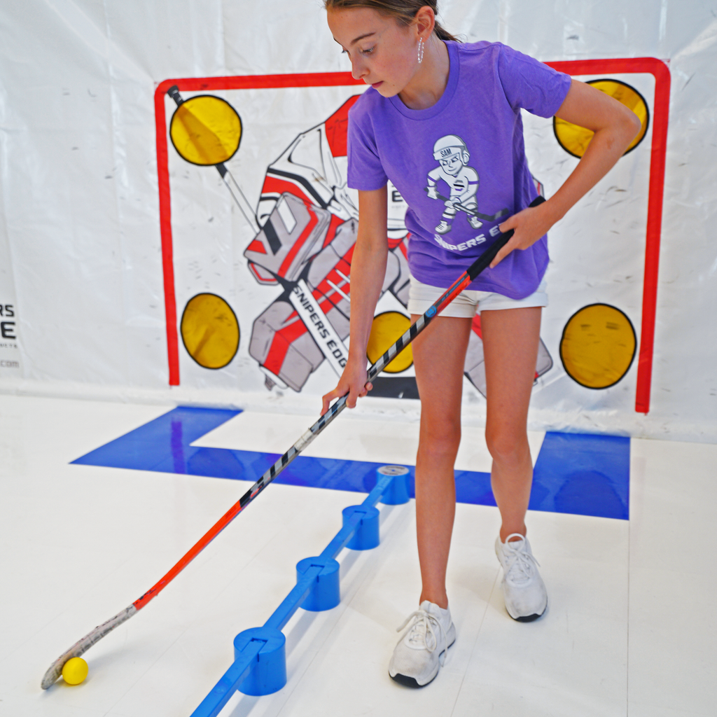 Girl in purple Sniper Sam shirt using yellow speed ball with Sweethands practicing hockey 
