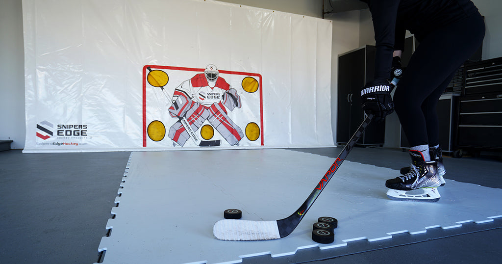 Hockey player wearing skates, standing on the Sniper's Edge synthetic ice and preparing to shoot towards Snipers Edge shooting tarp