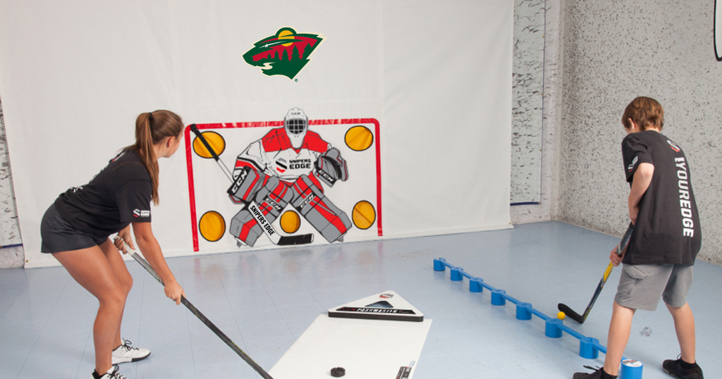 Teenage girl player using dryland pucks with PassMaster on shooting pad and about to shoot towards shooting tarp, while teenage boy player uses stickhandling balls with SweetHands stickhandling aid