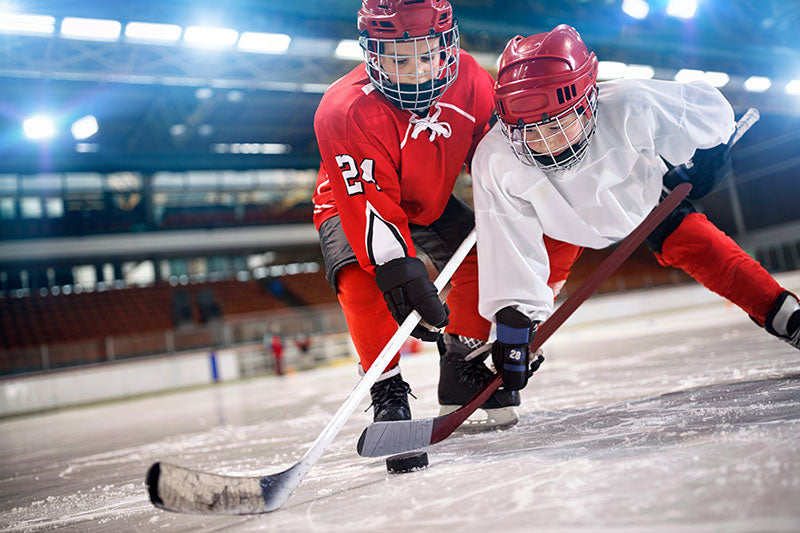 Two kids playing hockey using their sticks in the game 