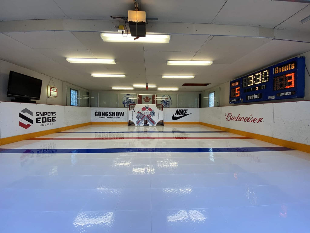 Elaborate home training center with white tiles, dark blue and red lines, perimeter boards, ultimate goalie, and scoreboard  