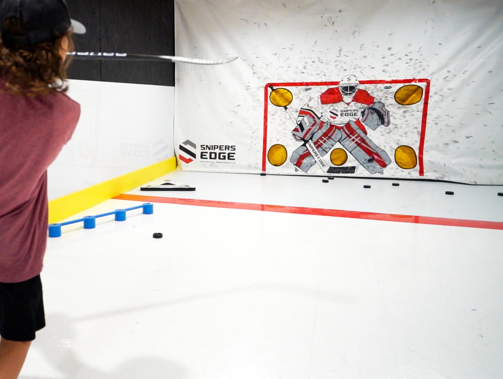 Youth player shooting pucks with white tiles and shooting tarp