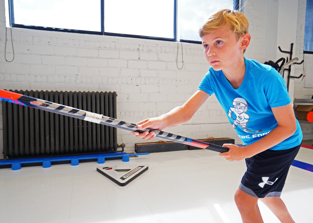 Youth player in neon Sniper Sam tshirt shooting a puck
