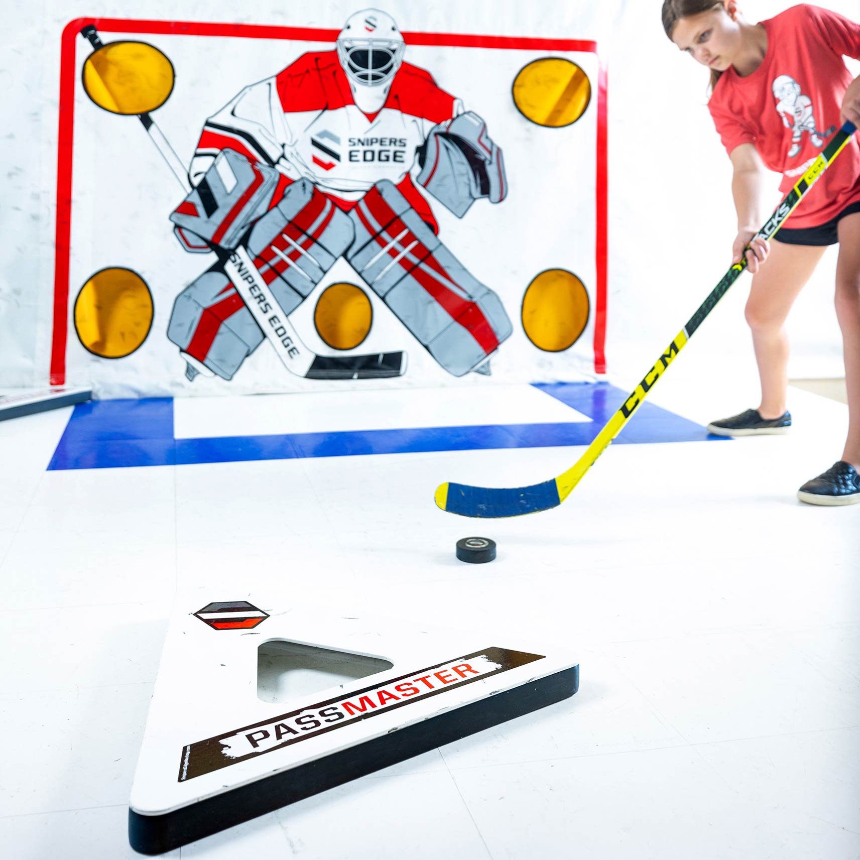 Player passing puck in front of goal on slick white tiles using the passmaster
