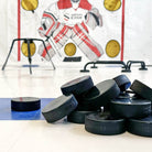 Pile of black pucks sitting on slick tiles in front of hockey net
